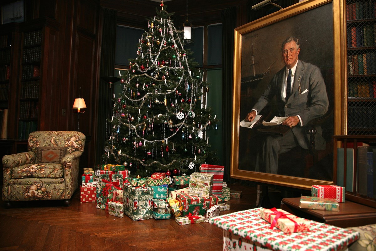 A large room with comfortable seating and a Christmas tree next to a large portrait of FDR.