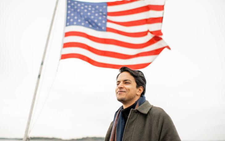 A picture of a man standing in front of an American flag