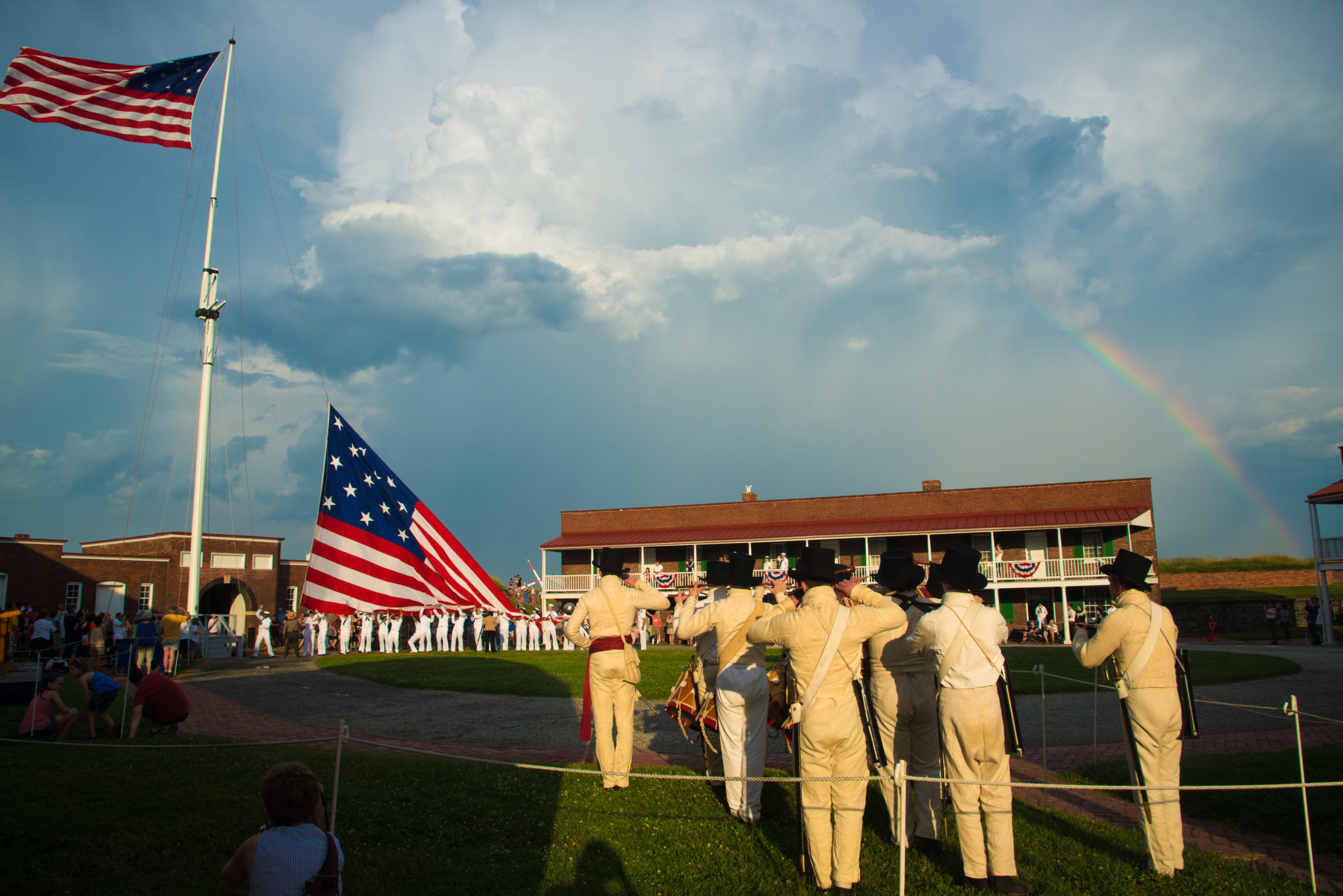 Uniformed military members assist with a flag change inside the fort.