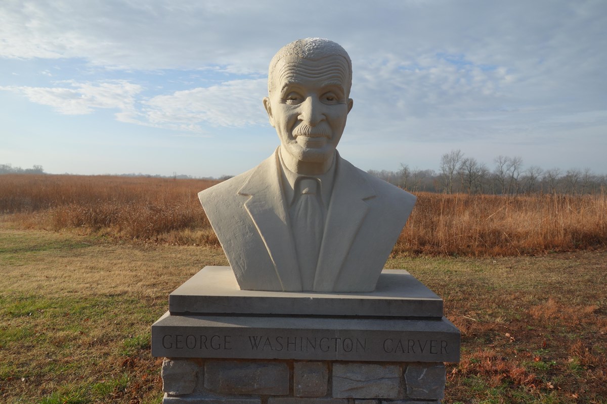 Bust of George Washington Carver surrounded by prairie.