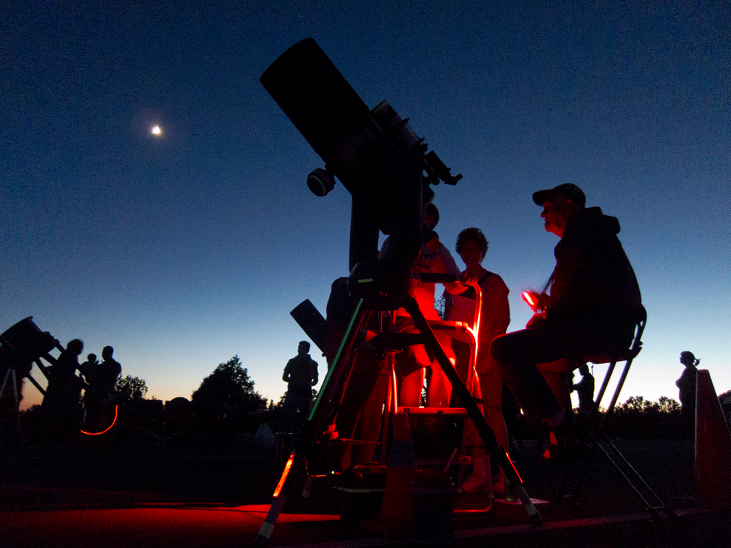Night Sky showing one bright star with astronomy telescopes set up and people viewing the sky