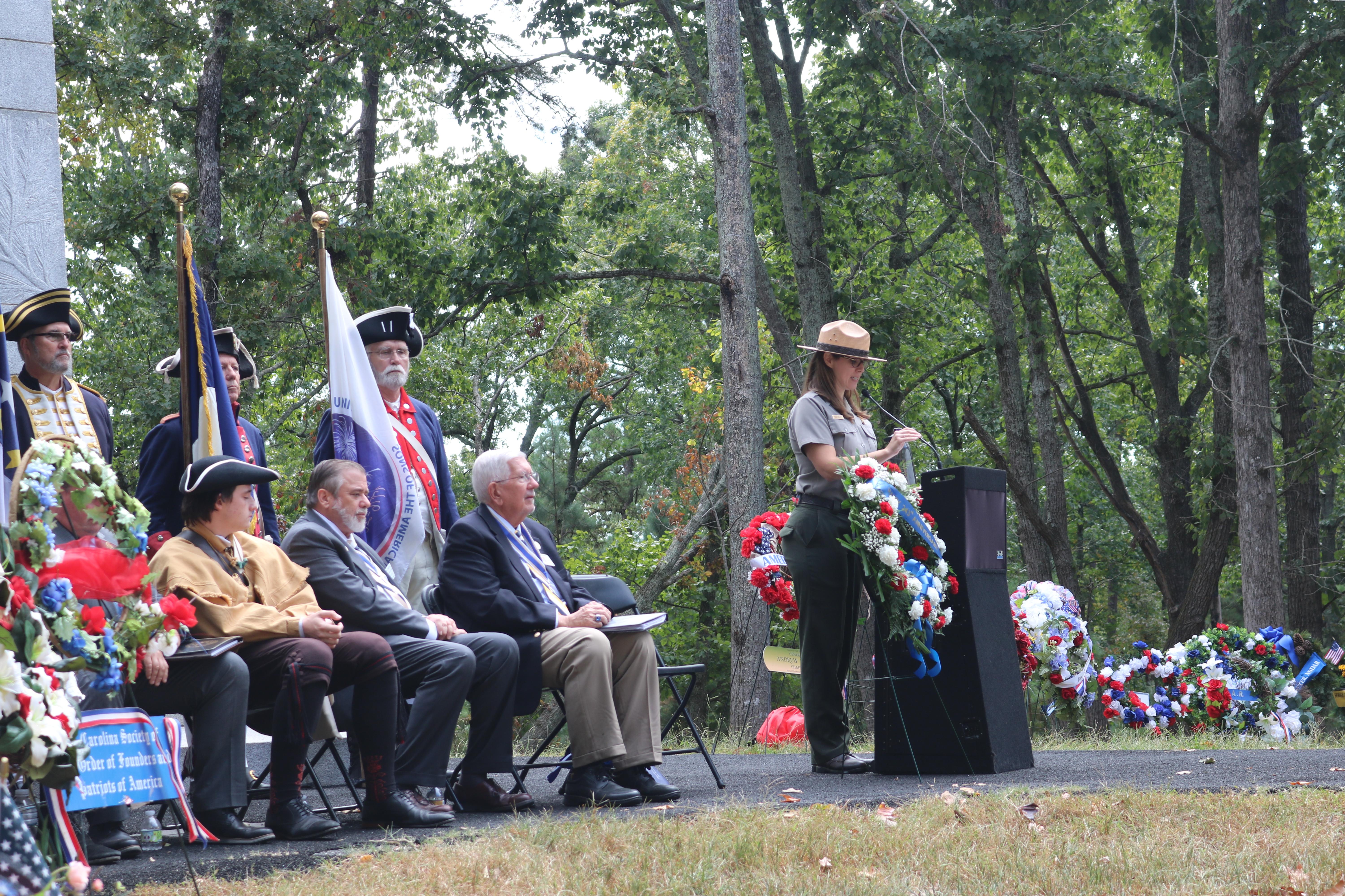 A park ranger speaks behind a podium with guests seated behind her.