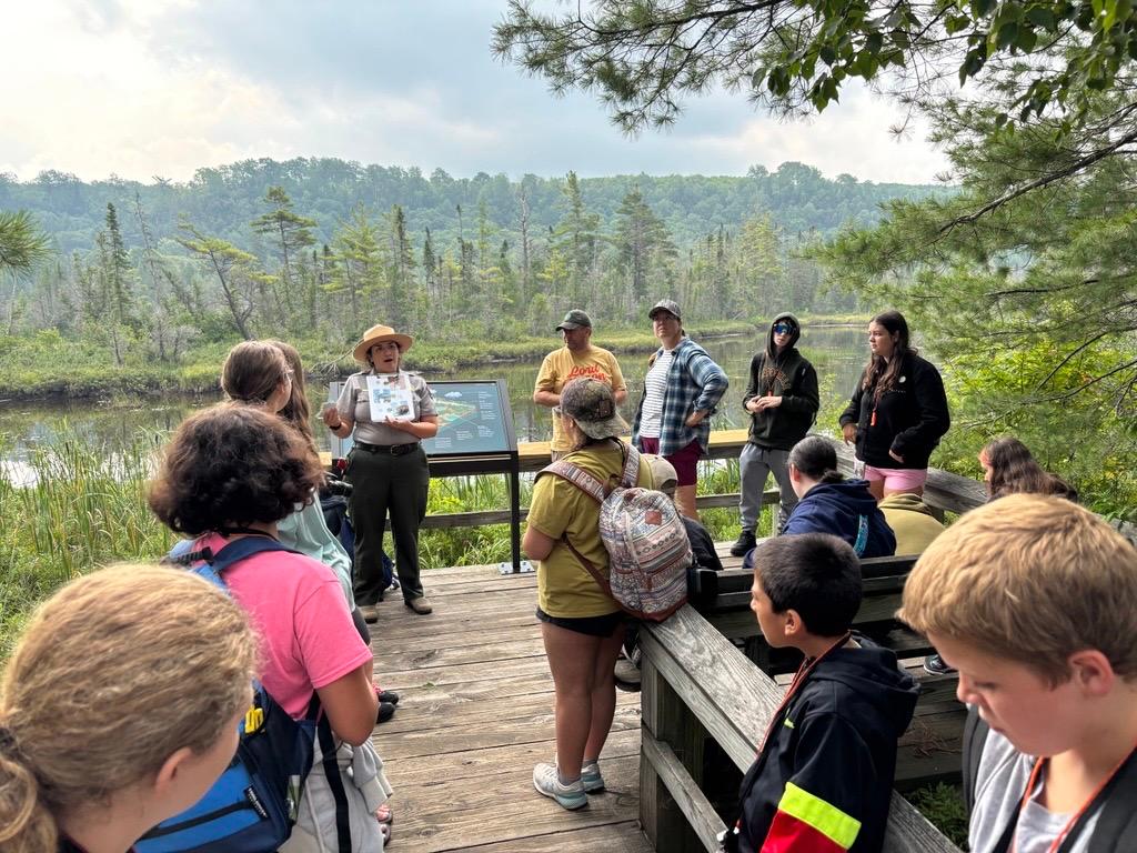 A ranger leads a program on a boardwalk in front of a wetland