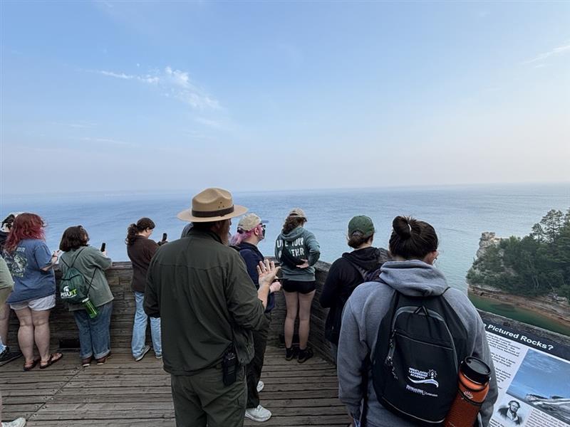 A ranger leads a guided tour on an overlook of a sandstone formation.