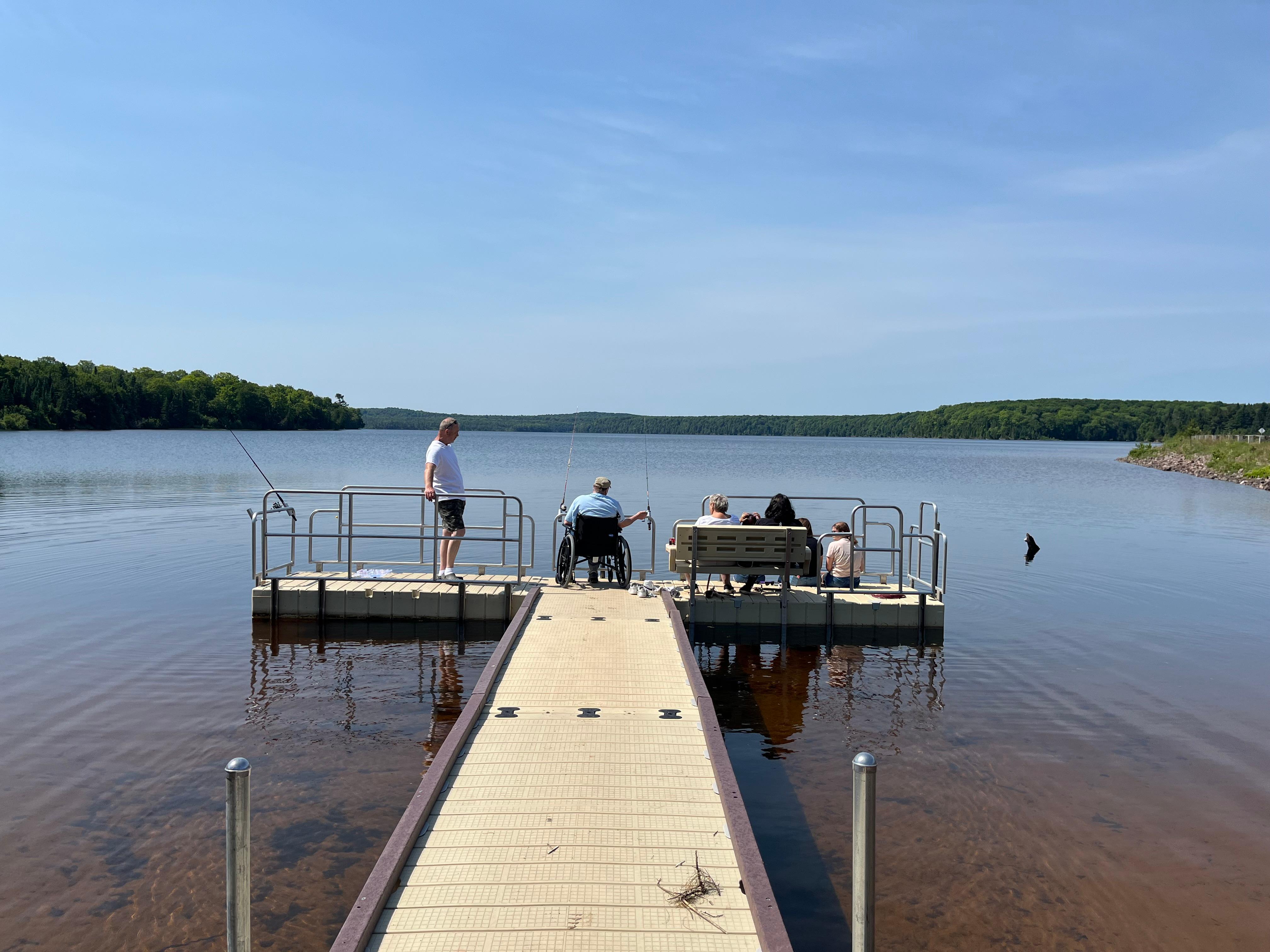 People fish from the end of a floating dock.
