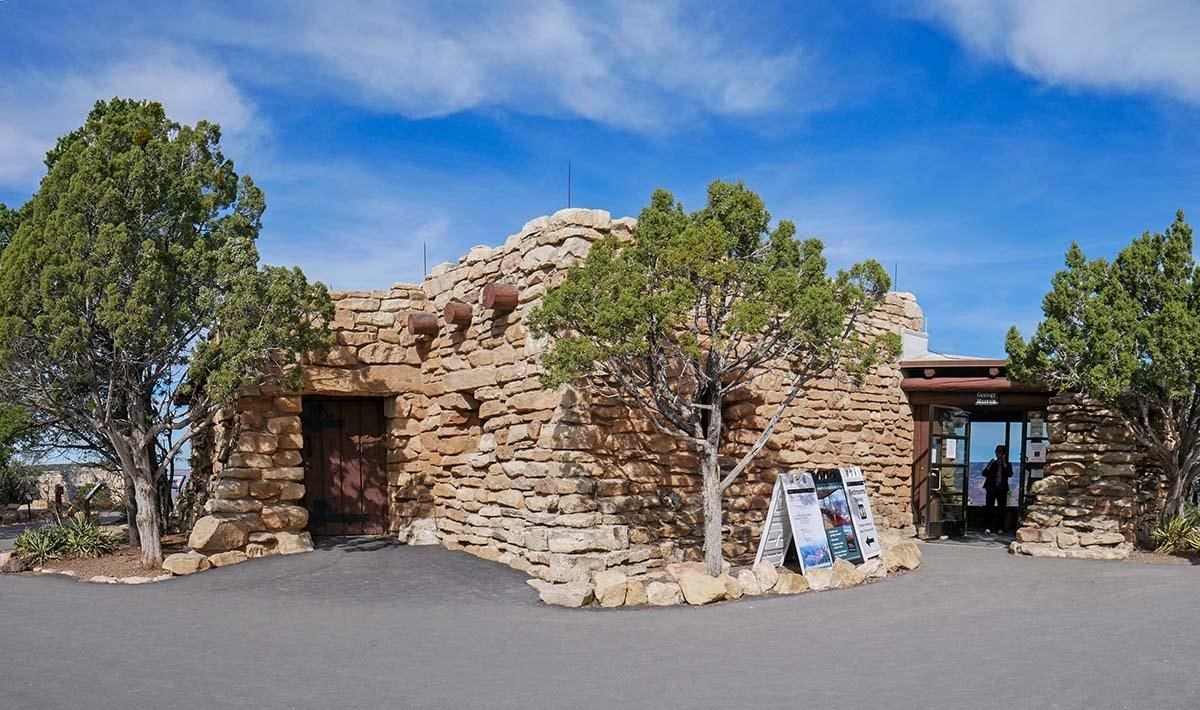 An irregularly-shaped one-story building, exterior walls are made of uniformly-sized boulders.