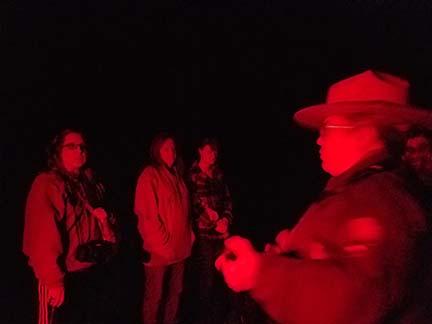 a ranger talking to visitors in the dark
