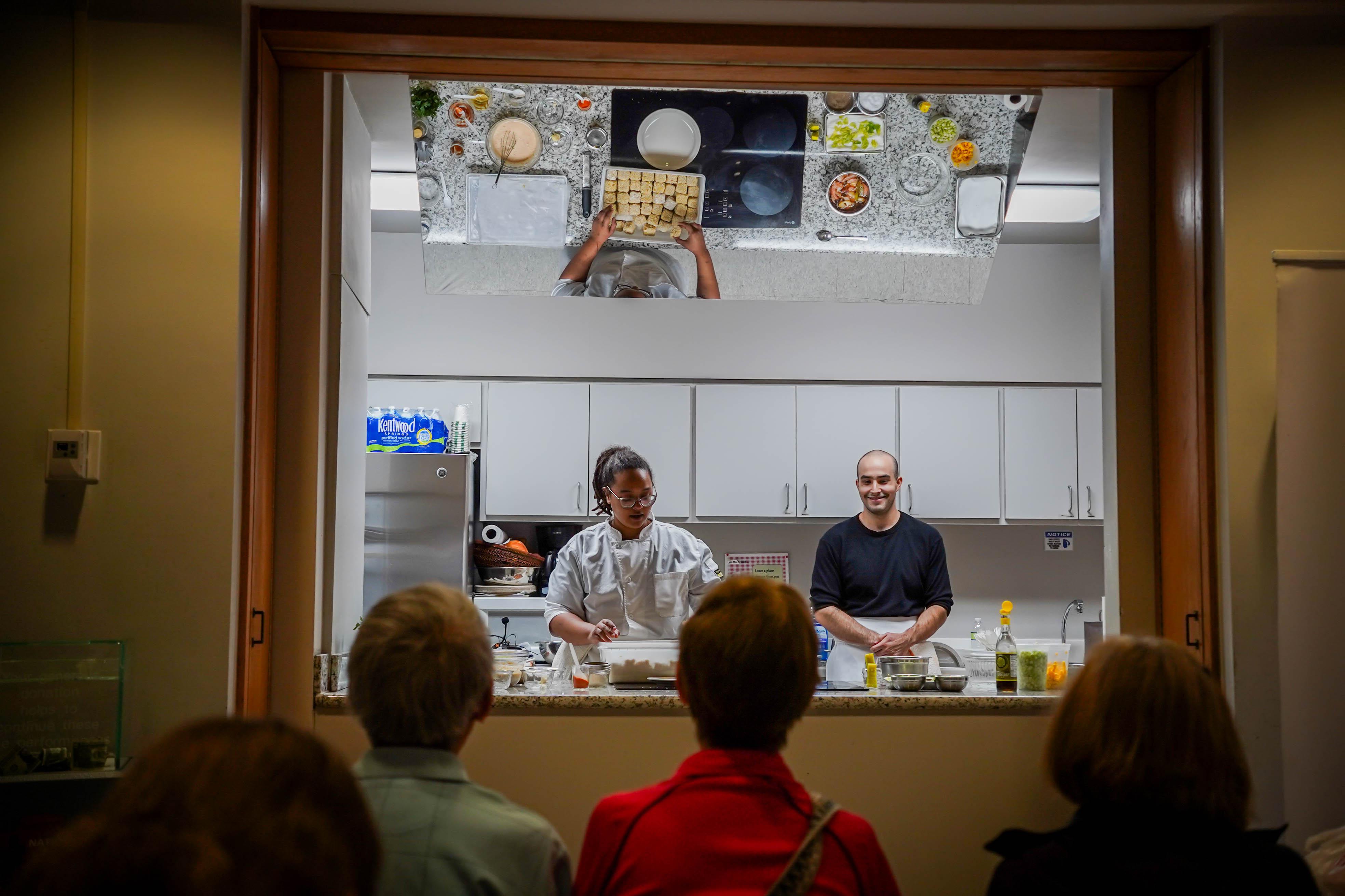 Audience members watch a cooking demonstration at the park.