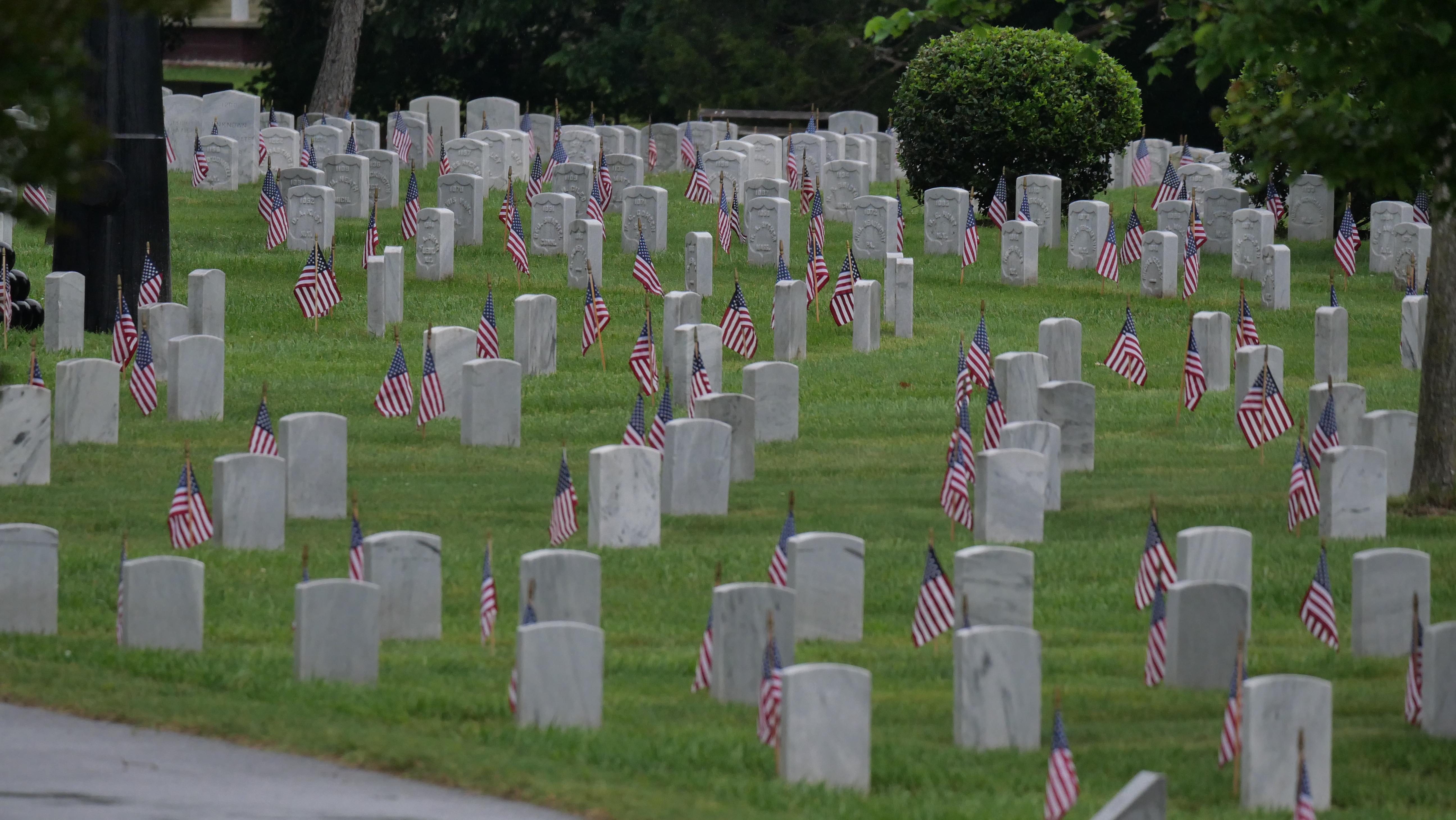 Small U. S. Flags in front of white marble headstones.