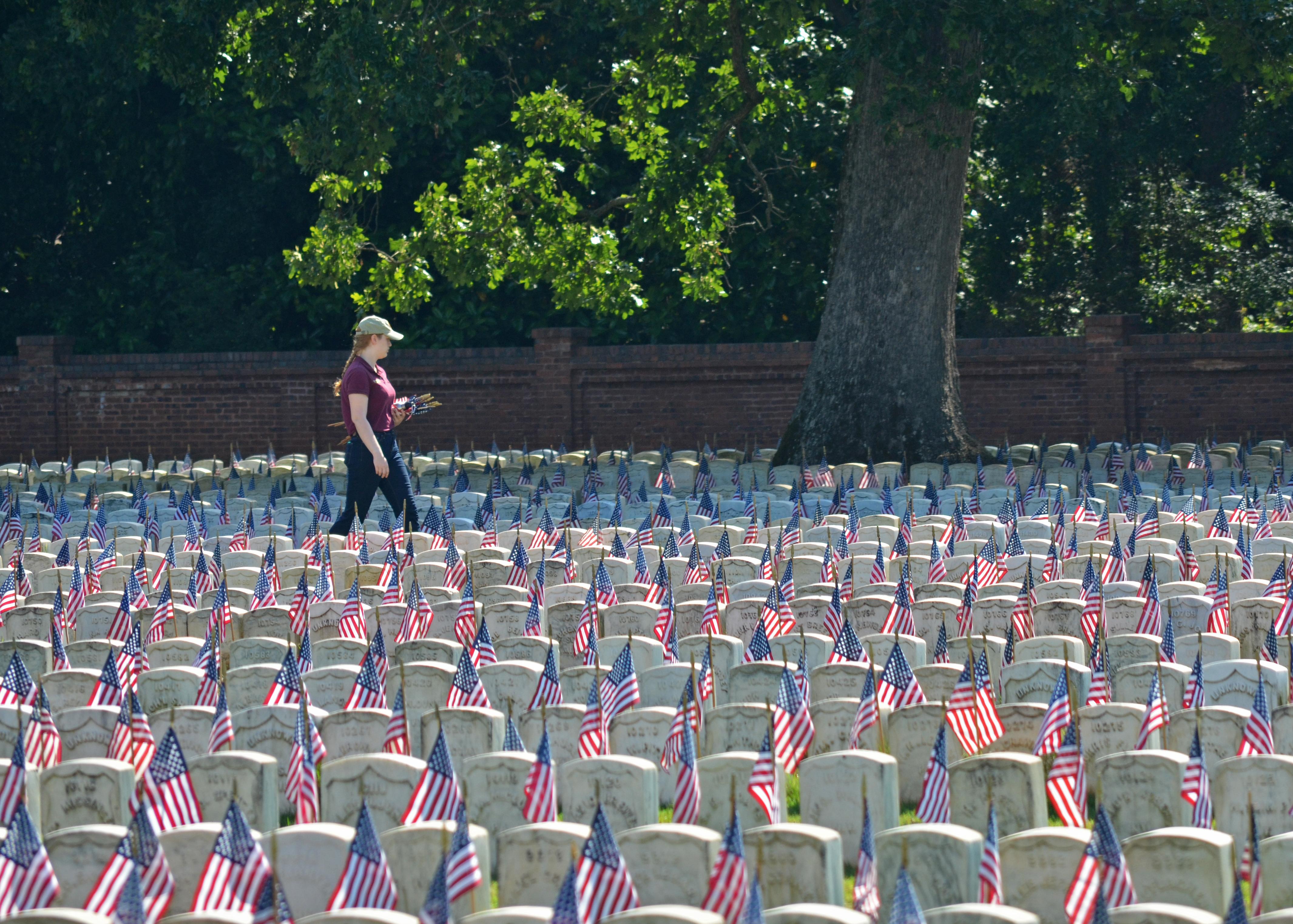 A park volunteer straightens flags in a Civil War section of Andersonville National Cemetery
