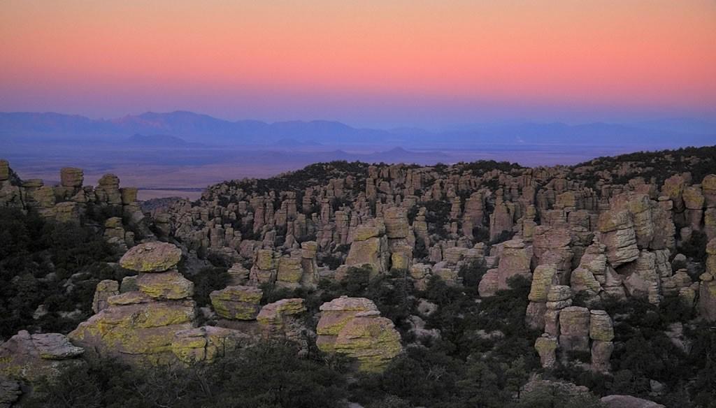 Rock pinnacles at Chiricahua National Monument under a colorful sunset sky.