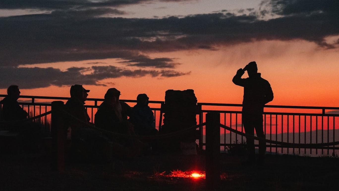 The sun goes down while a Ranger Talk takes place during a Night Sky Tour with visitors listening