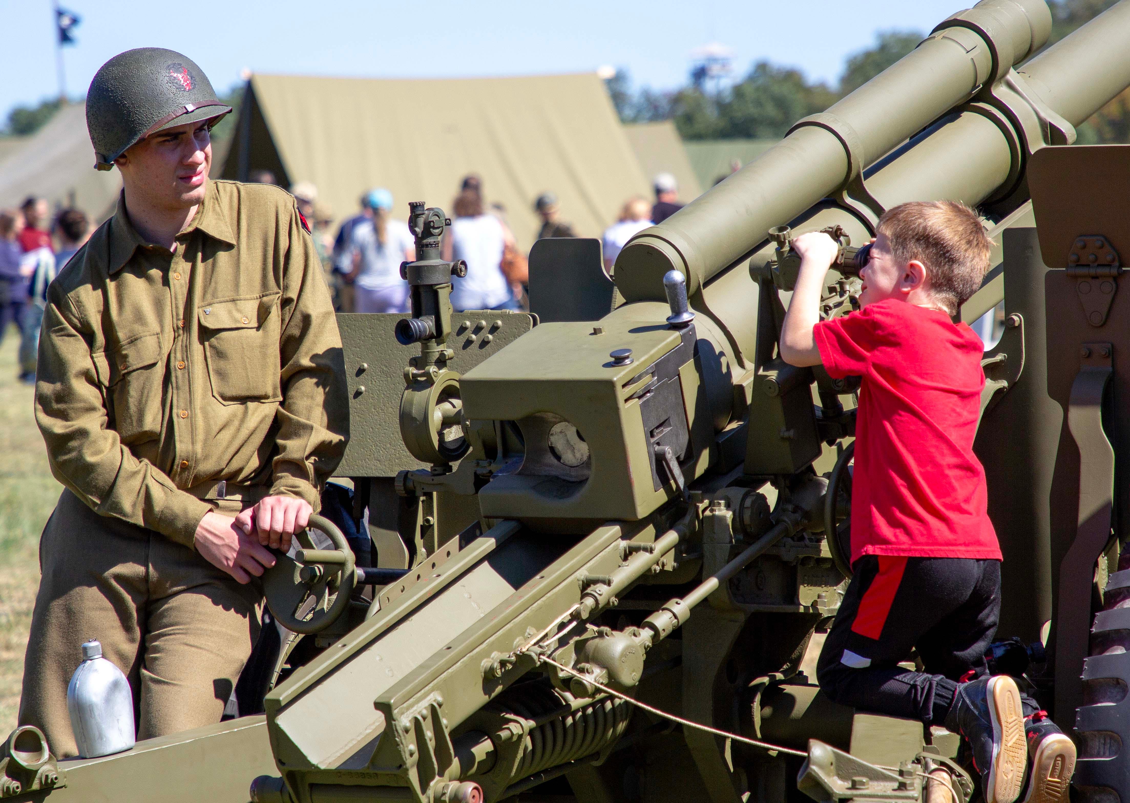 A young visitor looks through the scope at a WWII era cannon