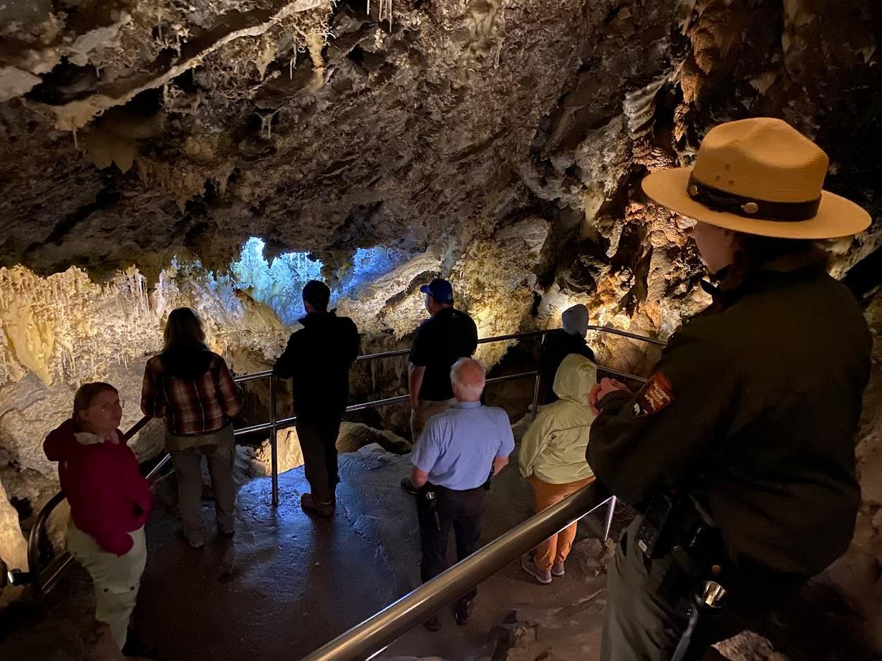 A ranger stands above a group of people inside a cave