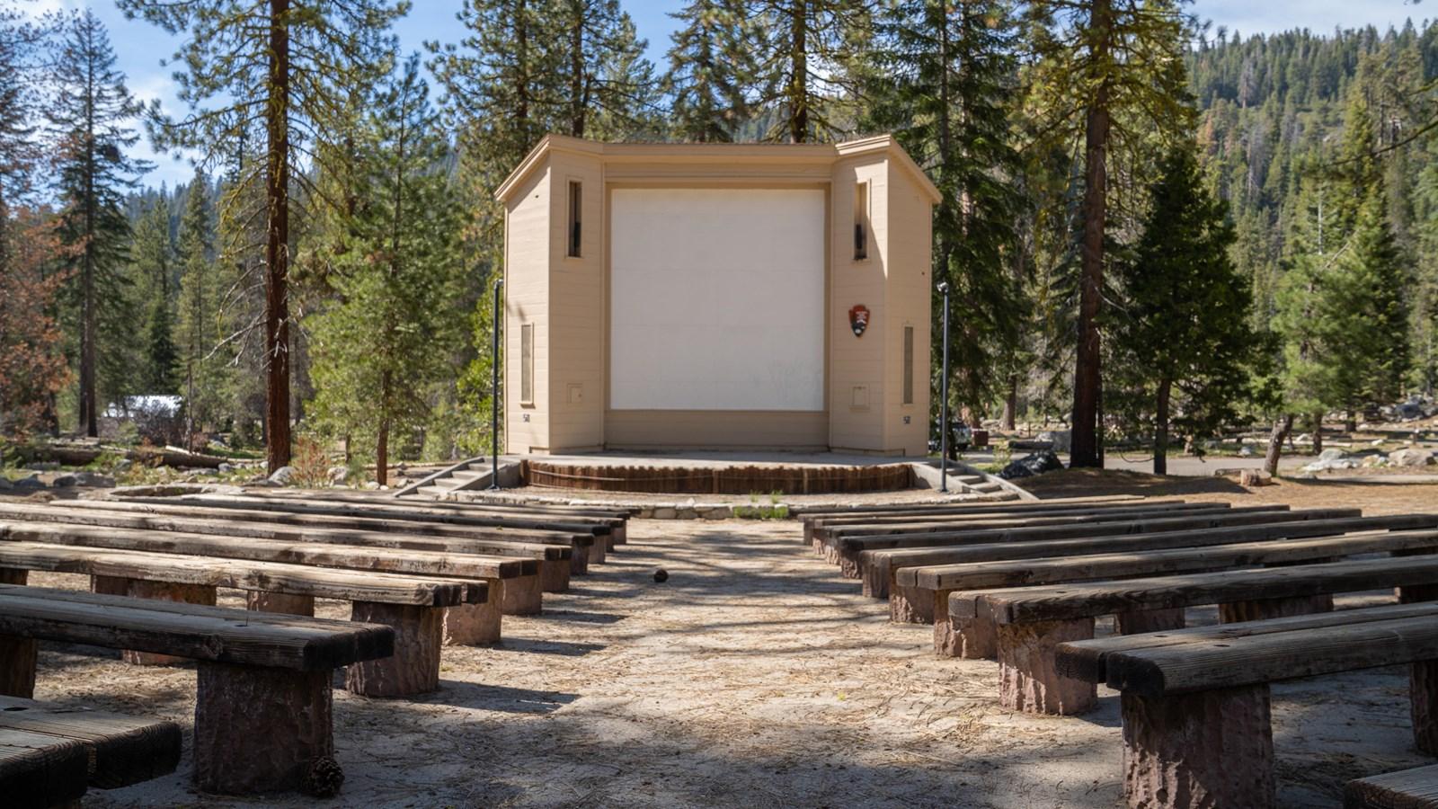 Rows of benches face a stage with a large projection screen