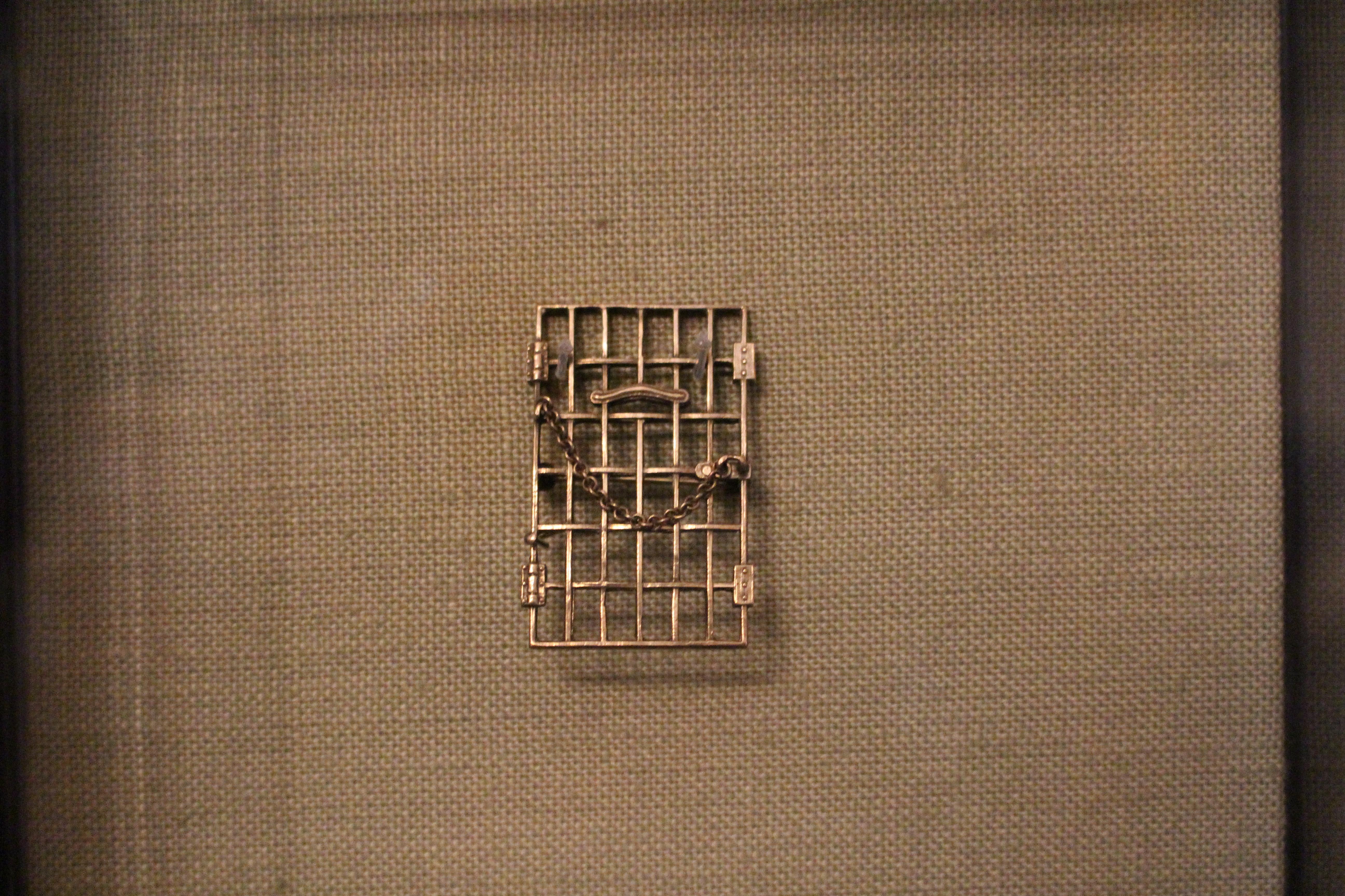 Rectangular metal pin resembling a jail door in museum exhibit case