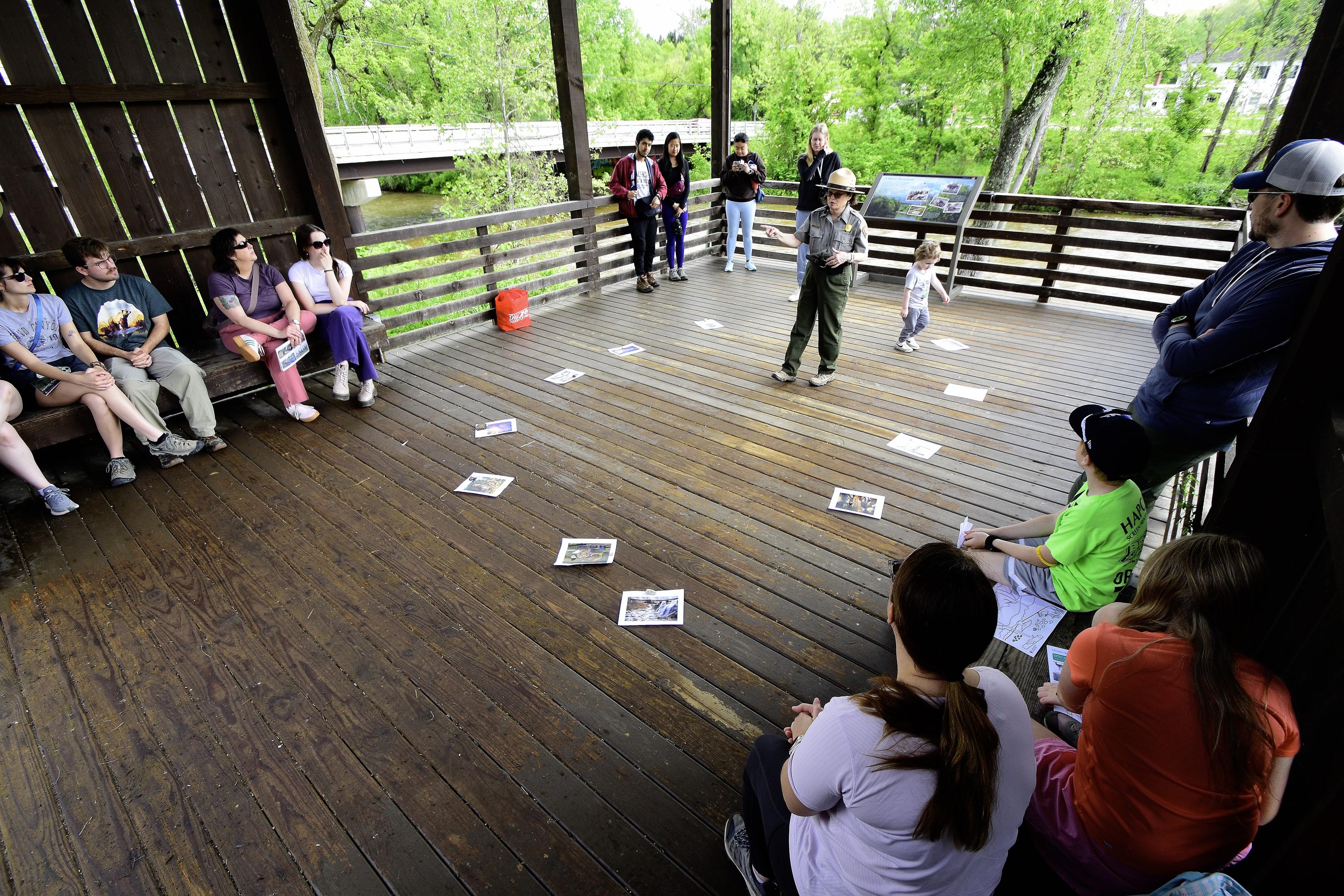 A park ranger talks with a group of visitors outside in a medium sized pole barn.