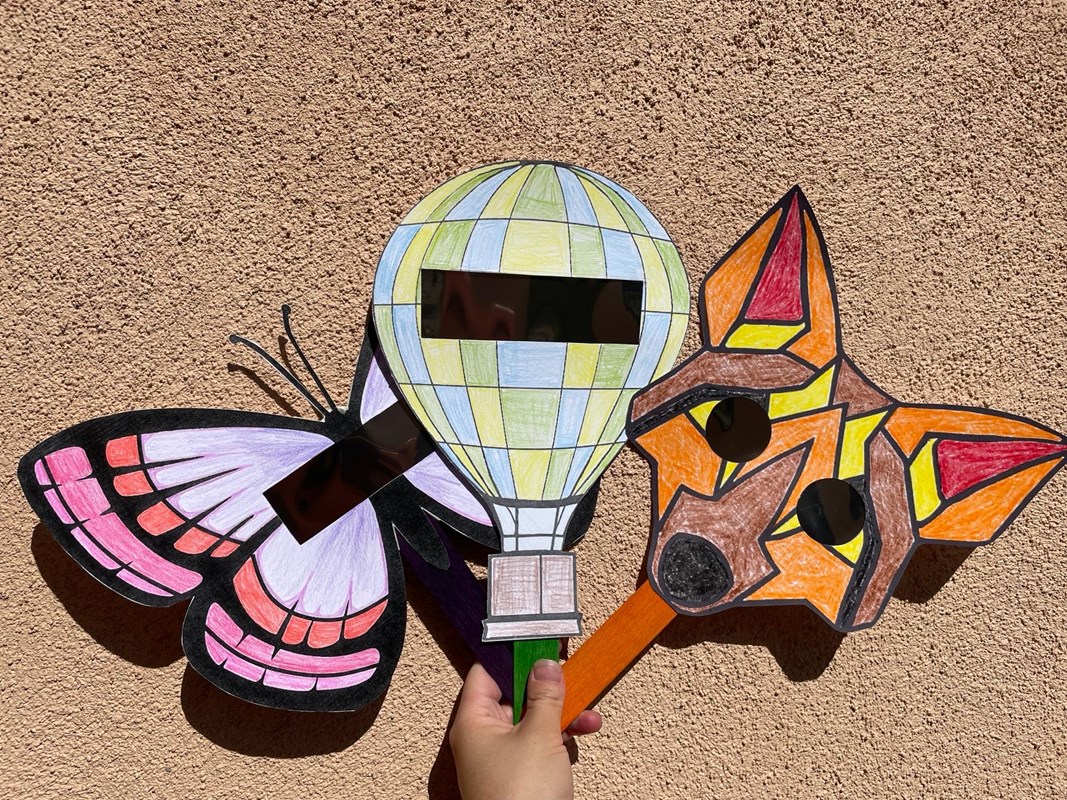 Three colorful children's masks with solar filters covering the eye holes.