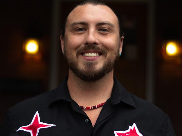 A man wearing a black shirt smiles.