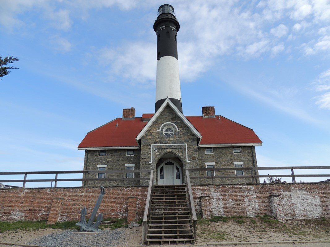 A lighthouse and keeper's quarters sit underneath a blue sky