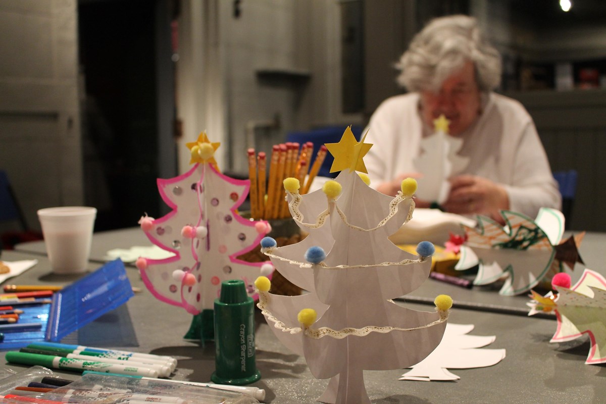 Paper tree craft in foreground with woman crafting in background