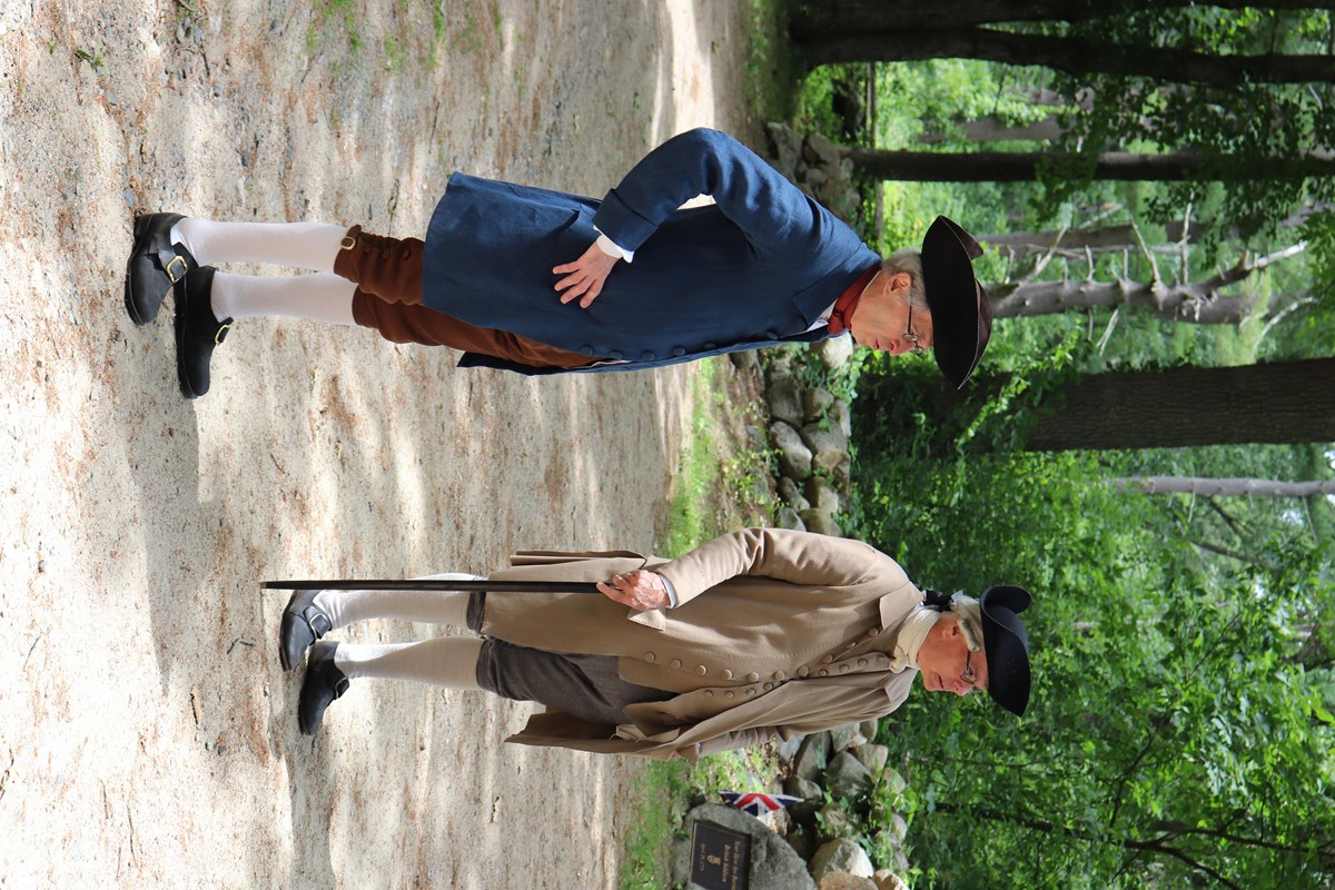 Two men in colonial clothing stand on the Battle Road Trail