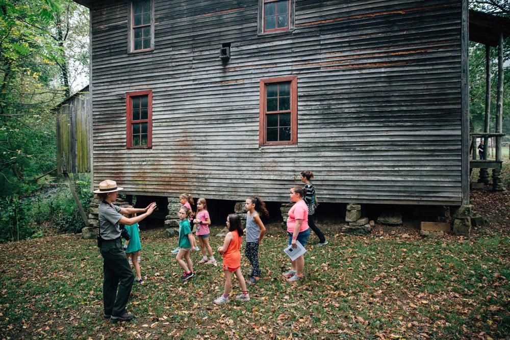Several young visitors tour the outside of the Boxley Grist Mill with a ranger.