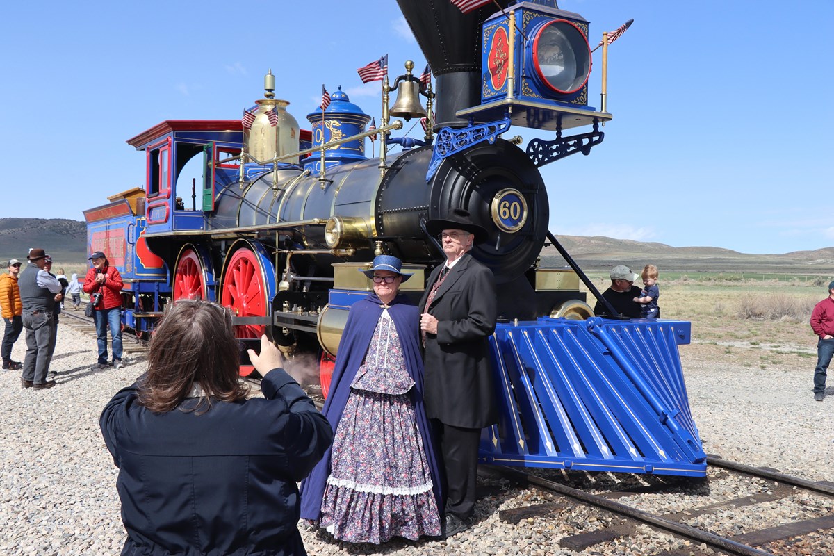 Reenactors stand in front of a steam locomotive