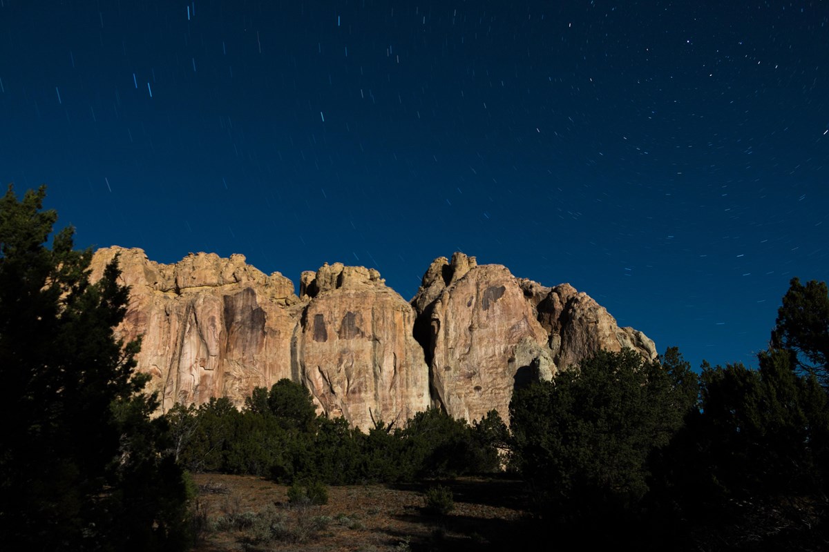 A tall sandstone promontory under a dark blue starry sky.