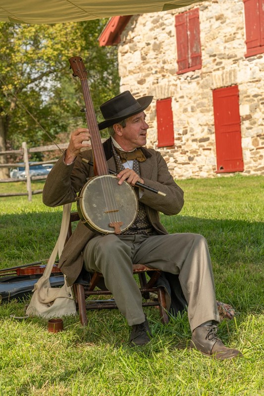 Park Ranger in 19th century attire plays a banjo.