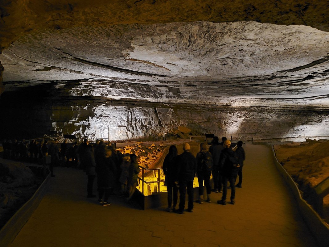 A large cave room with people standing near its center.