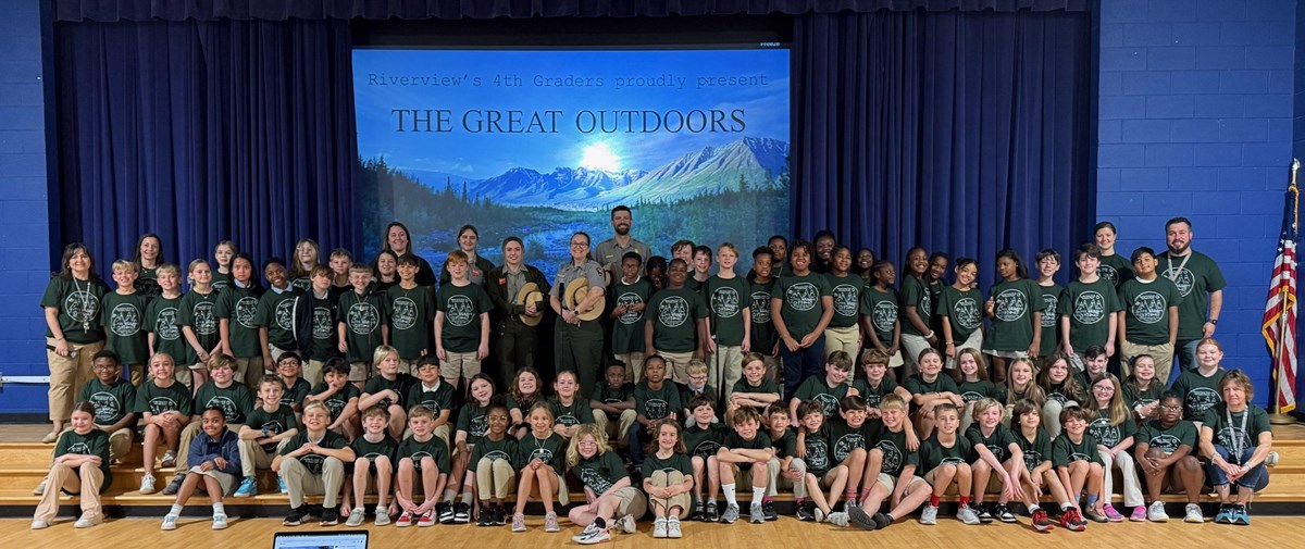 A group of students, teachers, and rangers stand on a stage.