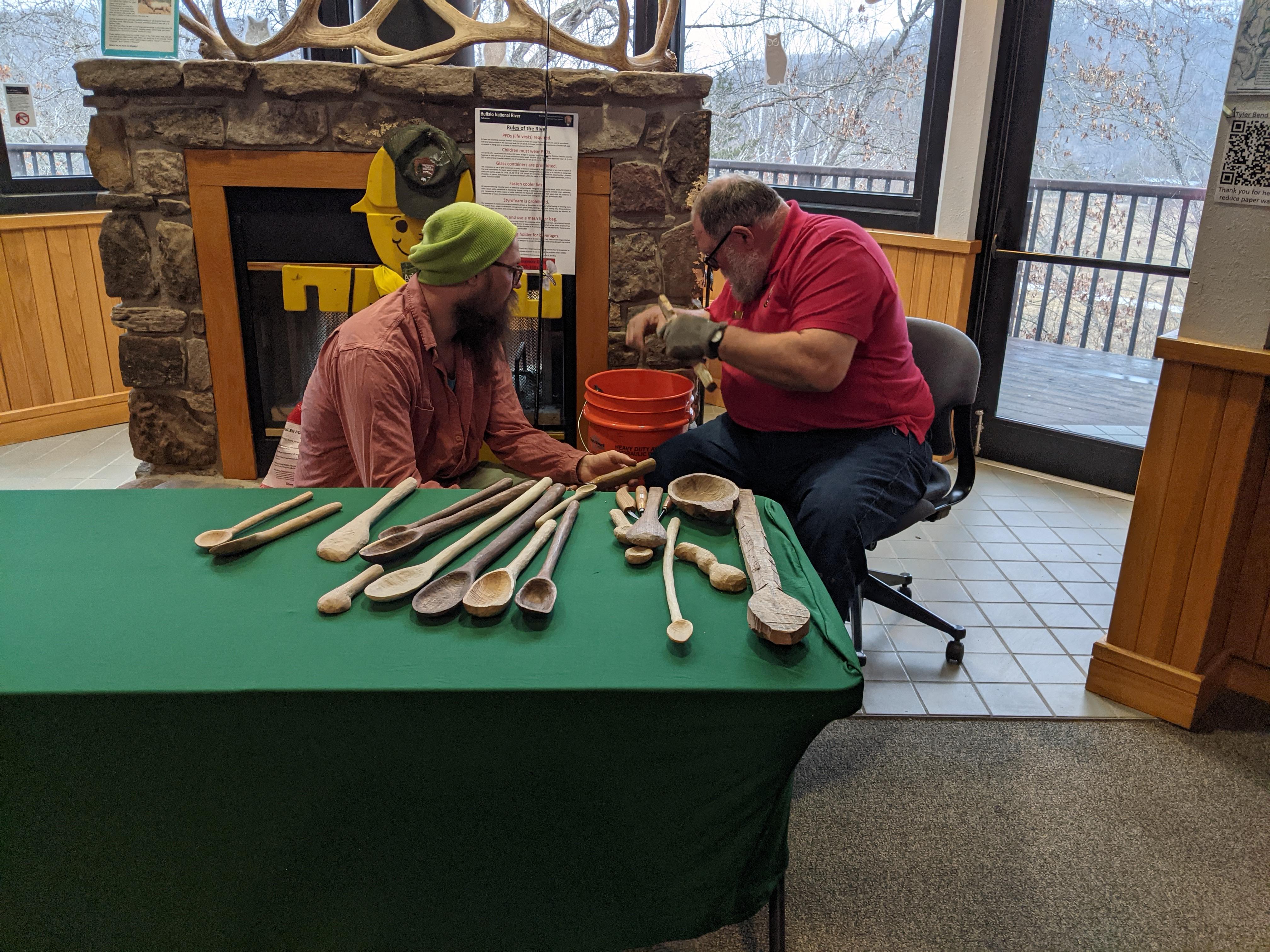BUFF Volunteer Ricky Hoyt whittles a spoon in front of a visitor.