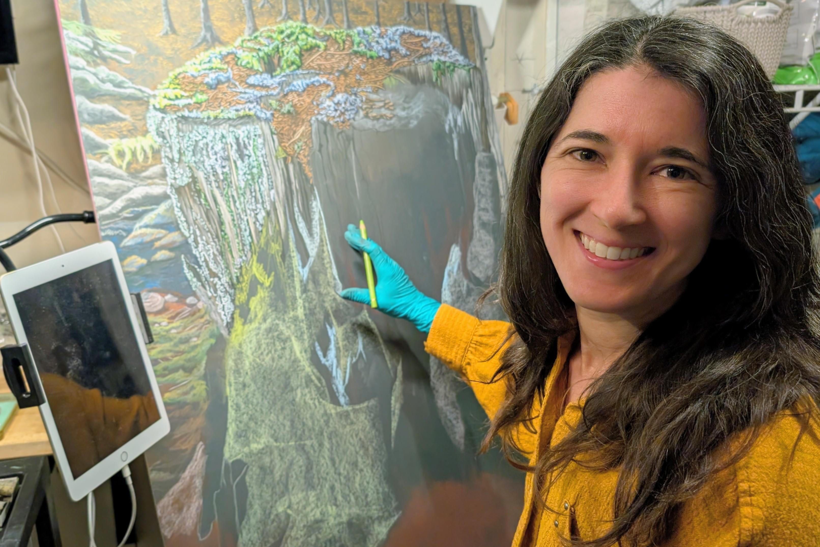 Artist Alexandra Bassett is working on a painting of a tree stump with moss and lichen in her studio