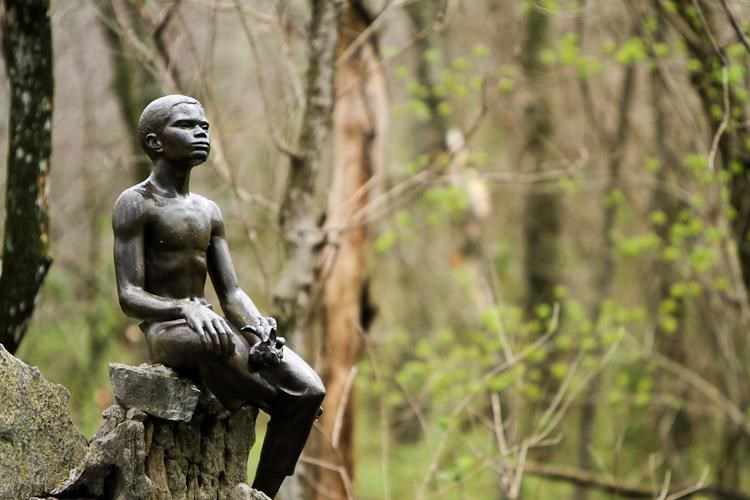 Bronze statue of young George Washington Carver holding a plant.