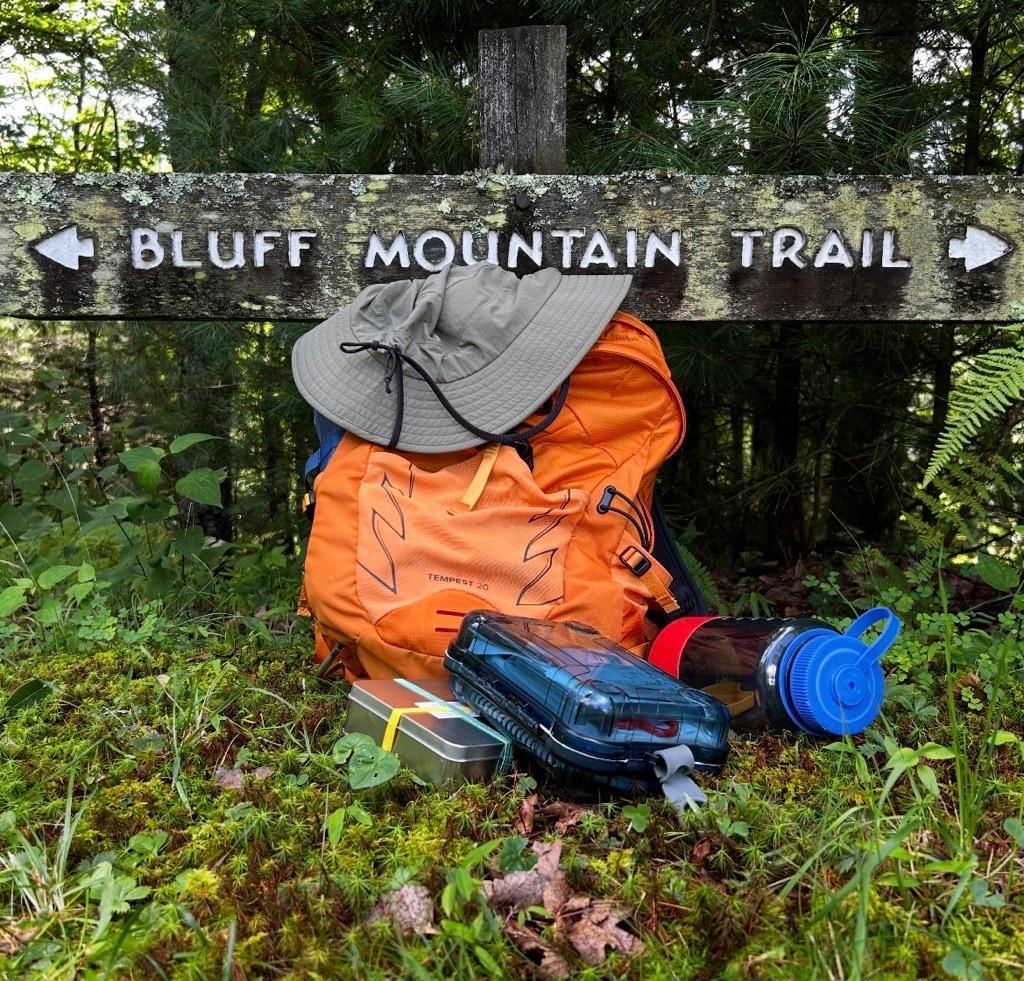 Hiking essential equipment sits on the ground.