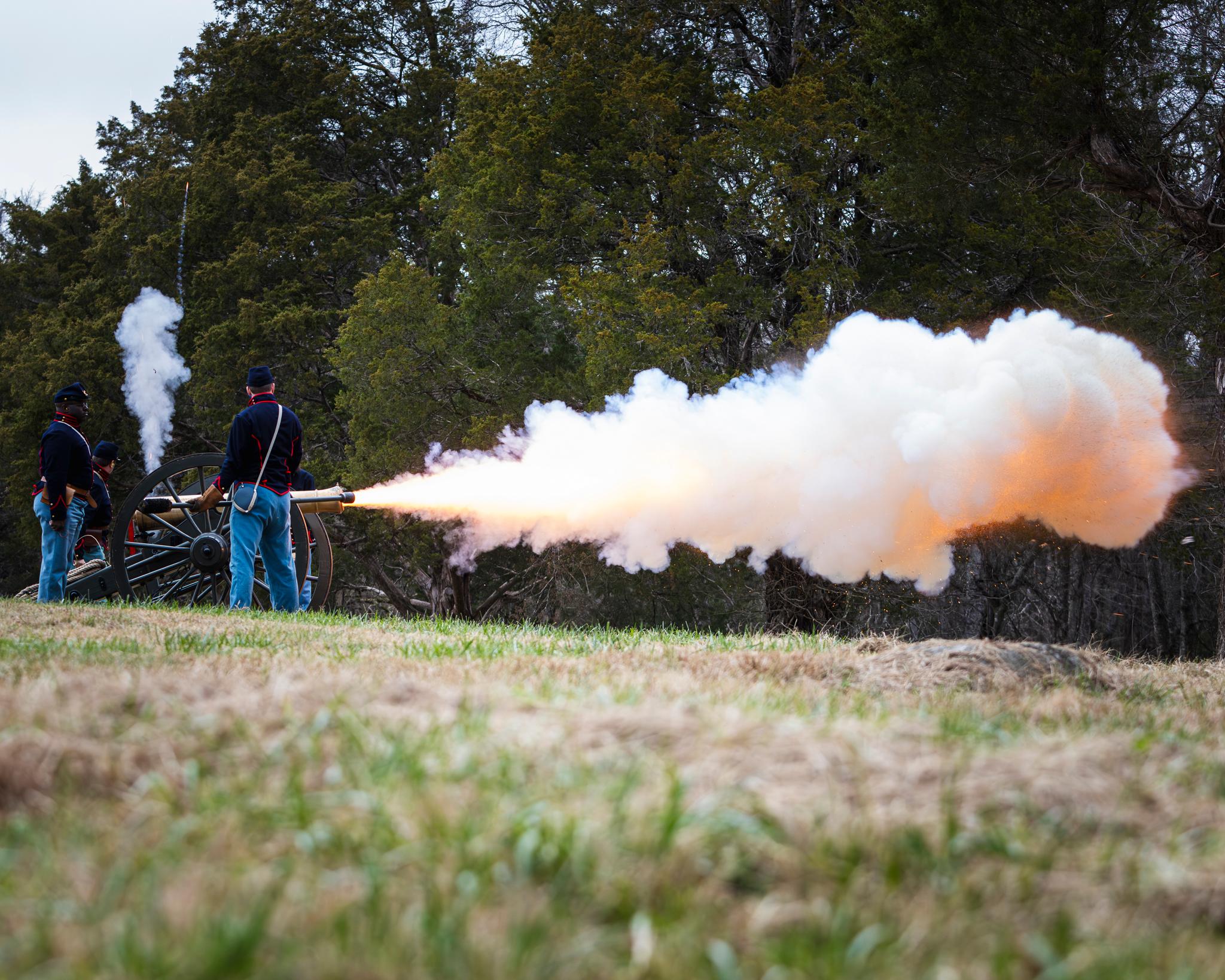 Flame and smoke emerge from the muzzle of a bronze cannon.