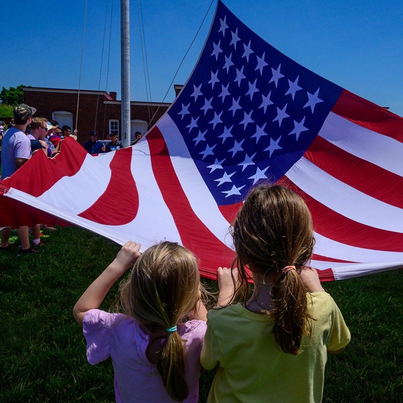 Children in foreground with 34-star flag being raised in Star Fort