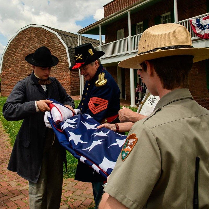 Ranger and living history volunteers in Civil War uniform folding U.S. flag