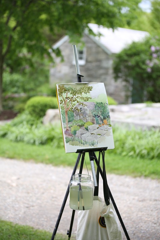 A painting of a grey shed on a easel.