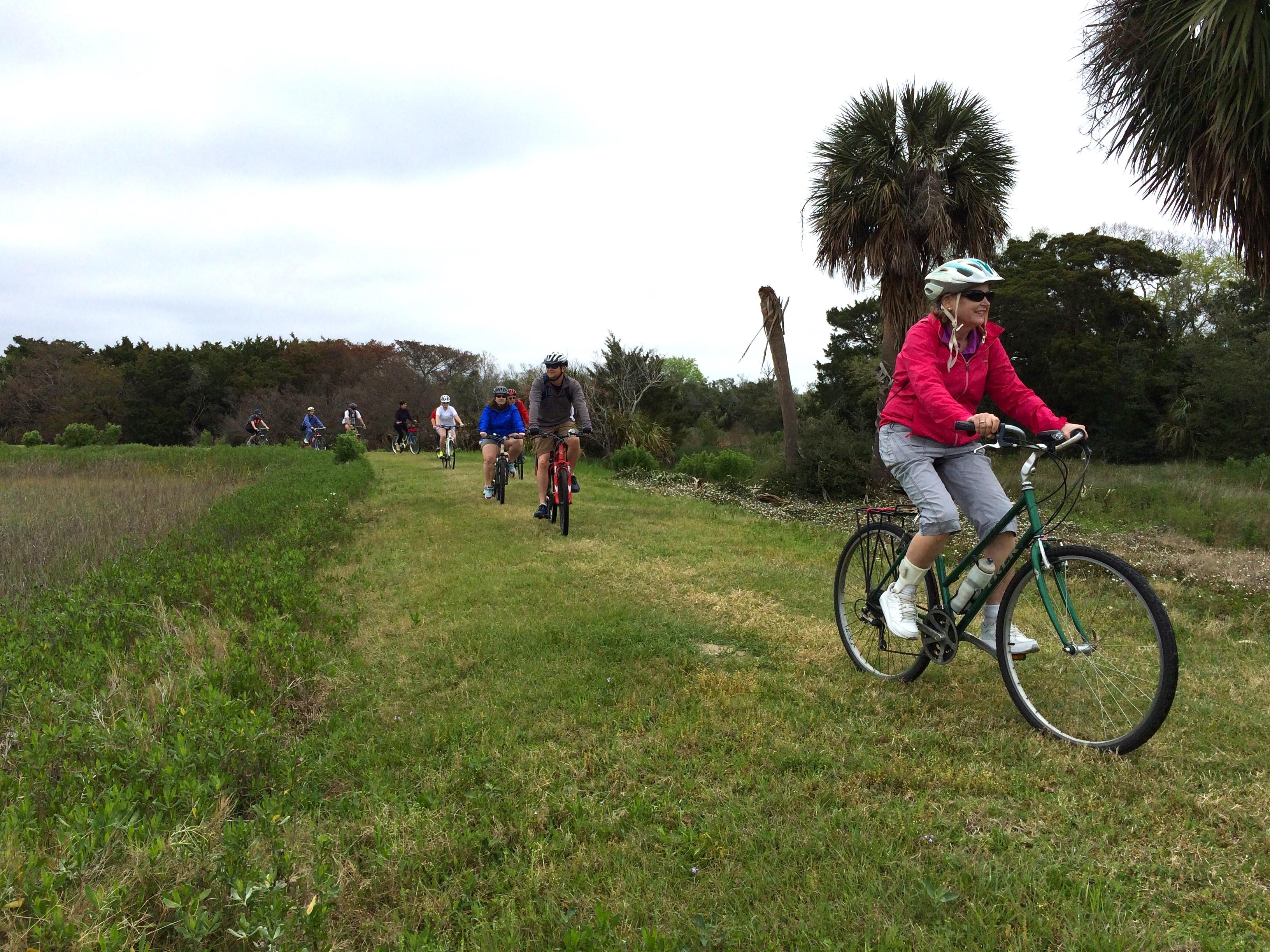 Several people riding bikes on a grassy dike.