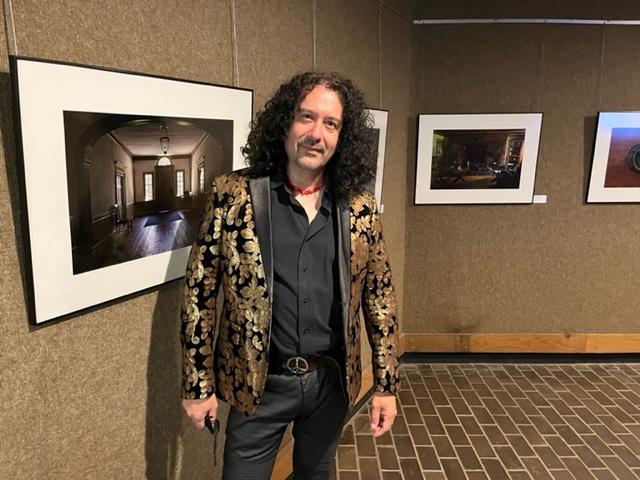 Man standing in front of wall with framed photography