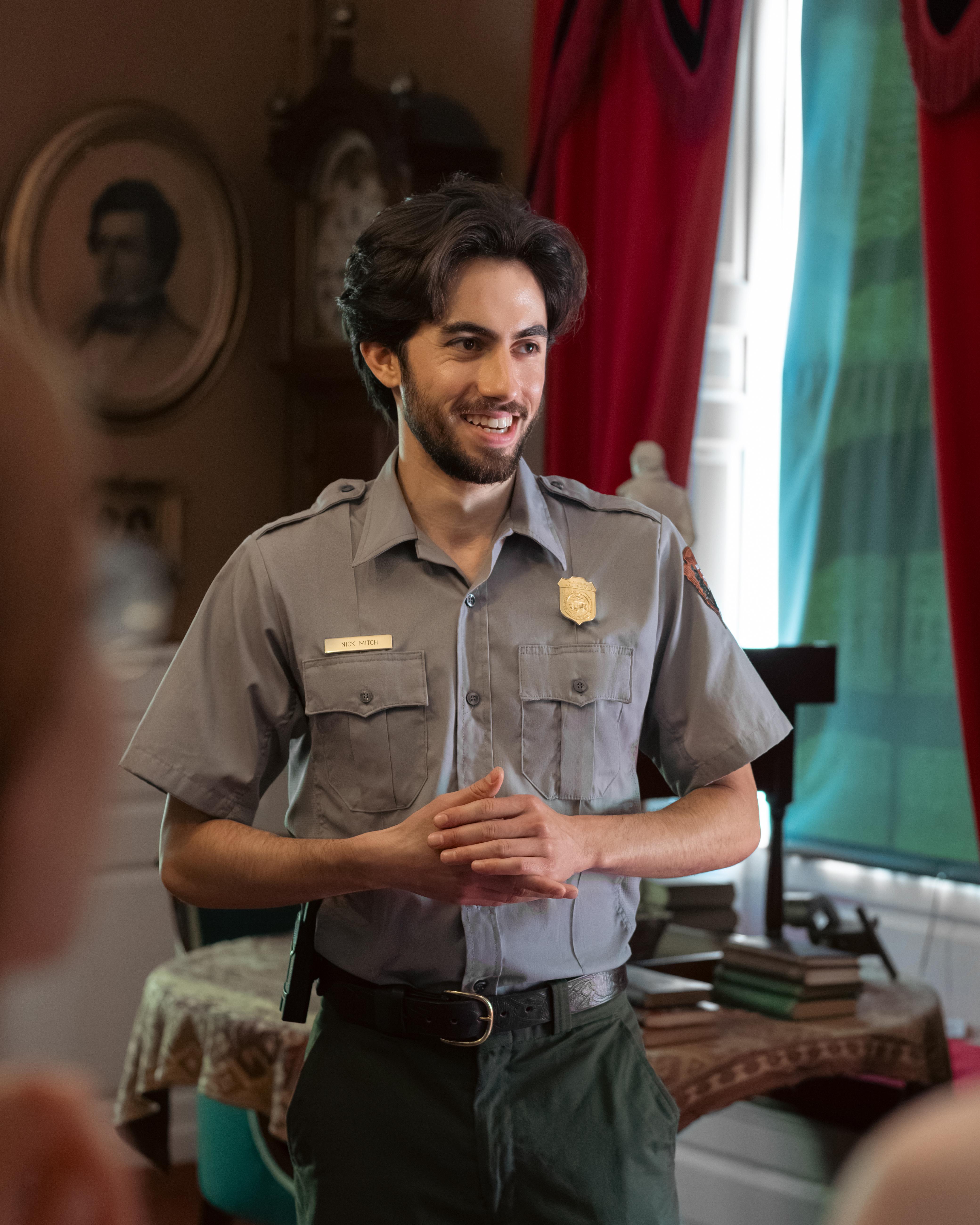 Smiling park ranger in a historic study with red curtains in background