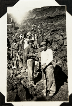 Black and white photo of laborers working on a rocky trail with no trees