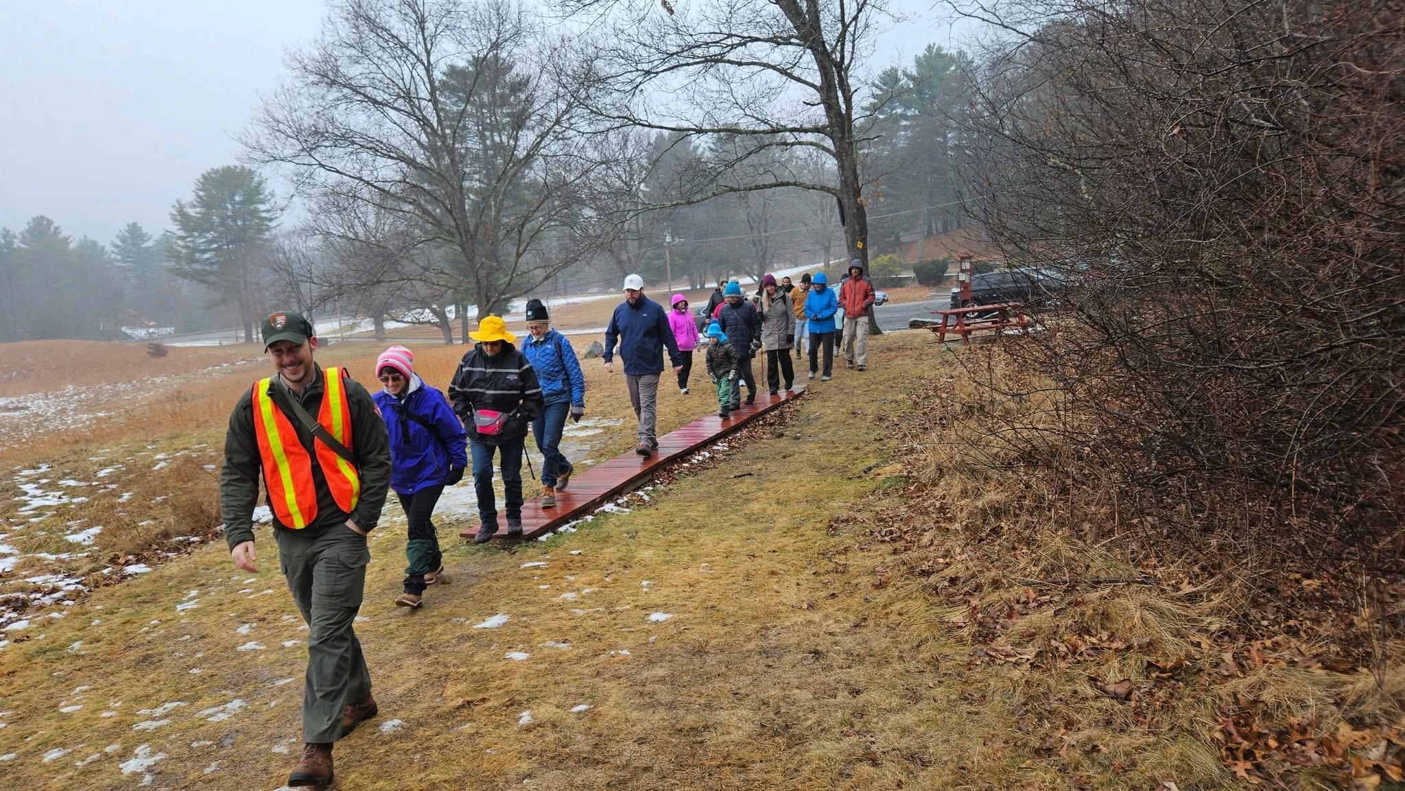 A ranger leading a group of people on a hike through the woods surrounded by trees