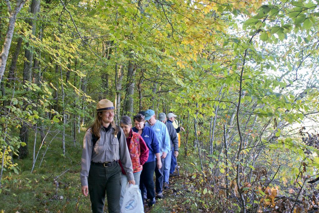 park ranger leads group of people along a trail through a forest