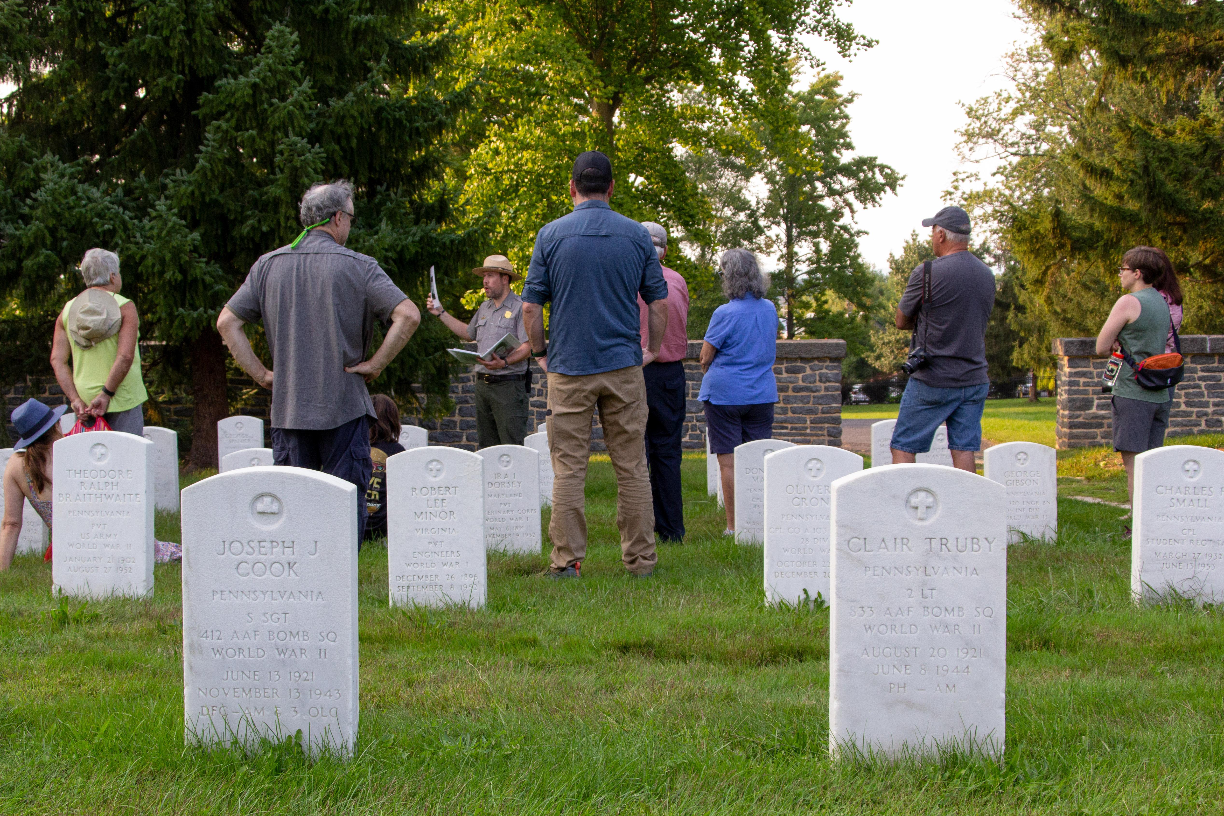 A group of visitors listens as a park ranger speaks in the national cemetery