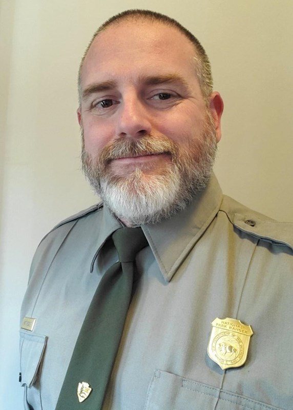 A man in a NPS uniform smiles into the camera