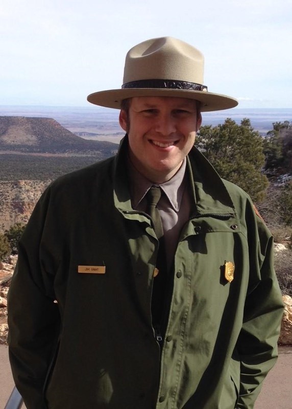 A uniformed park ranger smiles into the camera