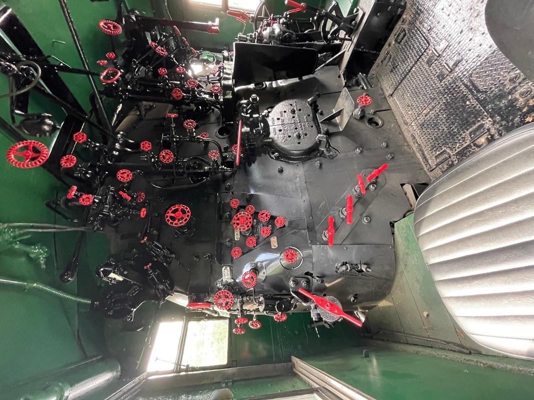 interior of locomotive cab with black undercoat, green roof, and over 30 red valves